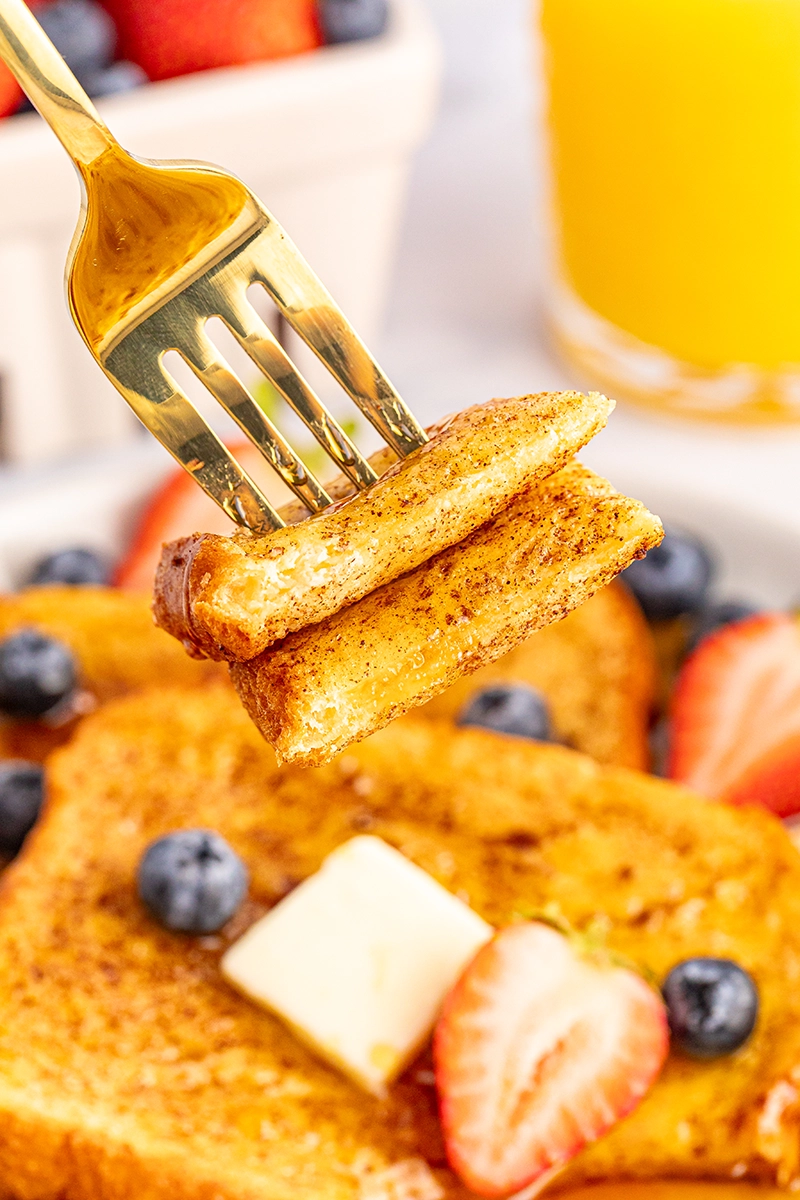 A fork is being used to eat french toast for one.